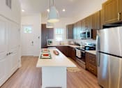 Thumbnail 2 of 48 - A kitchen with a white island in the middle and a refrigerator on the right.