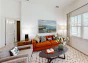 Thumbnail 4 of 48 - A living room with a grey couch, a coffee table, and a painting on the wall.
