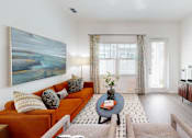 Thumbnail 3 of 48 - A living room with a couch, a coffee table, and a painting on the wall.