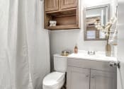 Thumbnail 6 of 14 - a bathroom with a toilet and a sink and a mirror