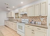 Thumbnail 10 of 26 - a kitchen with white cabinets and a tiled floor