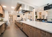 Thumbnail 16 of 34 - a large kitchen with a large island and stainless steel appliances at Magnolia Square, Naples, FL