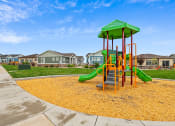 Thumbnail 32 of 34 - a playground with yellow mulch and houses in the background at The Villas at Prairie Center, Brighton