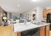 Thumbnail 4 of 44 - a kitchen island with a sink and a dishwasher in front of a living room with a