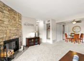 Thumbnail 3 of 40 - the living room has a stone fireplace and a dining room table and chairs at Silver Reef Apartments, Lakewood, CO, 80228