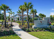 Thumbnail 45 of 46 - a sidewalk leading to a sign in front of a house with palm trees at Artesia at Lakewood Ranch Apartments, Bradenton, FL, 34211