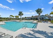 Thumbnail 32 of 46 - a swimming pool with palm trees and a building in the background at Artesia at Lakewood Ranch Apartments, Florida 34211