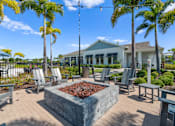 Thumbnail 37 of 46 - a patio with chairs and a fire pit and a building in the background at Artesia at Lakewood Ranch Apartments, Bradenton