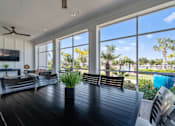Thumbnail 27 of 46 - a patio with a wooden table and chairs and large windows at Artesia at Lakewood Ranch Apartments, Bradenton, FL
