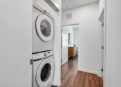 Thumbnail 20 of 40 - a white washer and dryer in a white laundry room with a wooden floor at Odyssey, Florida, 33905
