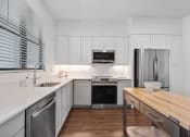 Thumbnail 1 of 40 - a kitchen with white cabinets and stainless steel appliances and a wooden counter top at Odyssey, Fort Myers, FL, 33905