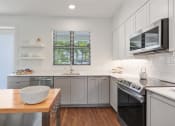 Thumbnail 3 of 40 - a kitchen with stainless steel appliances and a wooden table at Odyssey, Florida, 33905