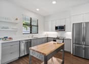 Thumbnail 2 of 40 - a kitchen with stainless steel appliances and a wooden table at Odyssey, Fort Myers