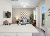 Thumbnail 4 of 37 - a kitchen island with a white counter top in front of a living room at Soleil at Canyon Trails Apartments, Arizona