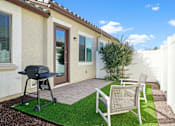 Thumbnail 11 of 37 - a backyard patio with a grill and two chairs at Soleil at Canyon Trails Apartments, Goodyear, 85338