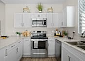 Thumbnail 14 of 37 - a large white kitchen with stainless steel appliances and white cabinets at Soleil at Canyon Trails Apartments, Arizona, 85338