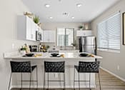 Thumbnail 15 of 37 - an open kitchen with a large island with three black stools at Soleil at Canyon Trails Apartments, Goodyear, AZ, 85338