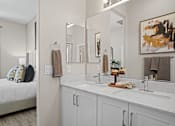 Thumbnail 20 of 37 - a bathroom with a sink and a mirror and a bedroom with a bed at Soleil at Canyon Trails Apartments, Goodyear
