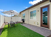 Thumbnail 28 of 37 - a backyard patio with a table and chairs and an umbrella at Soleil at Canyon Trails Apartments, Goodyear, AZ, 85338