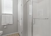 Thumbnail 12 of 43 - a white bathroom with a glass shower and a white toilet at Sienna at South Mountain Apartments, Laveen, AZ