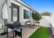 Thumbnail 14 of 43 - a backyard with a grill and chairs and a lawn at Sienna at South Mountain Apartments, Laveen, Arizona