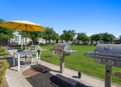 Thumbnail 35 of 43 - a patio with two bbq grills and a table with an umbrella at Sienna at South Mountain Apartments, Laveen, Arizona