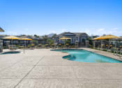 Thumbnail 32 of 43 - a swimming pool with patio furniture and umbrellas next to a resort style pool at Sienna at South Mountain Apartments, Laveen, 85339