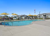 Thumbnail 33 of 43 - a swimming pool with yellow umbrellas in front of apartment buildings at Sienna at South Mountain Apartments, Laveen, AZ, 85339
