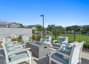Thumbnail 37 of 43 - furnished patio with blue and white chairs and a firepit at Sienna at South Mountain Apartments, Laveen, 85339