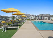 Thumbnail 34 of 43 - a pool with lounge chairs and umbrellas next to a pool at Sienna at South Mountain Apartments, Arizona, 85339