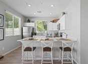 Thumbnail 19 of 43 - a kitchen with a white island with three stools at Sienna at South Mountain Apartments, Arizona, 85339