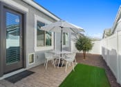 Thumbnail 31 of 43 - patio with stone and turf and table with chairs and umbrella at Sienna at South Mountain Apartments, Laveen