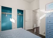 Thumbnail 14 of 33 - a bedroom with blue closets and white doors and a bed at Olive Queen Creek Apartments, Queen Creek, AZ, 85142