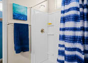 Thumbnail 12 of 33 - a small bathroom with a shower and blue towels at Olive Queen Creek Apartments, Queen Creek, AZ, 85142