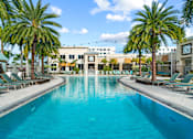 Thumbnail 47 of 65 - A large swimming pool surrounded by palm trees and lounge chairs. at Centre Pointe Apartments, Melbourne