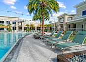 Thumbnail 51 of 65 - A pool area with lounge chairs and a palm tree. at Centre Pointe Apartments, Melbourne, FL, 32940