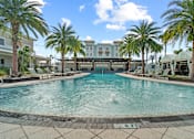 Thumbnail 49 of 65 - A pool surrounded by palm trees and lounge chairs. at Centre Pointe Apartments, Melbourne, Florida