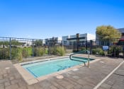 Thumbnail 24 of 33 - a swimming pool with a metal fence around it and a building in the background at Olive Queen Creek Apartments, Arizona