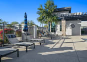 Thumbnail 29 of 36 - a pool with lounge chairs and umbrellas in front of a building at Bella Grace, Chandler, 85225