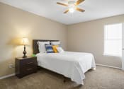 Thumbnail 10 of 29 - bed with white blanket and orange and blue pillows next to a window