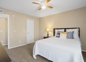 Thumbnail 11 of 29 - white bed with orange and blue pillows and fan above bed