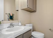 Thumbnail 17 of 29 - bathroom with brown cabinets, white sink and toilet