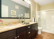 Thumbnail 24 of 49 - a bathroom with a large mirror and a toilet next to a shower at Skye at Arbor Lakes, Maple Grove, Minnesota