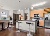 Thumbnail 3 of 34 - a kitchen with stainless steel appliances and an island with bar stools at The Millennium Towne Center Apartments, Baton Rouge, LA