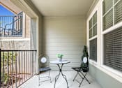 Thumbnail 19 of 34 - a patio with two chairs and a table on a balcony at The Millennium Towne Center Apartments, Baton Rouge, 70806
