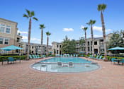 Thumbnail 32 of 34 - a large pool with chairs and umbrellas in front of apartment buildings at The Millennium Towne Center Apartments, Baton Rouge, LA, 70806