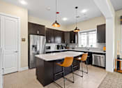 Thumbnail 12 of 33 - a kitchen with a large island with three chairs and a stainless steel refrigerator at The Landing Apartment , Hazlet, 07730