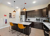 Thumbnail 11 of 33 - a kitchen with a large island with two orange chairs at The Landing Apartment , Hazlet