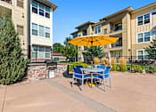 Thumbnail 38 of 48 - a patio with a table and chairs and an umbrella in front of an apartment building