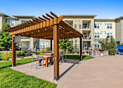 Thumbnail 41 of 48 - a patio with a pergola and tables in front of an apartment building